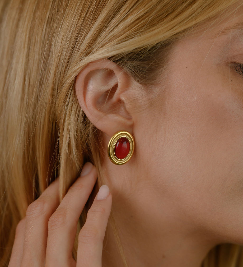 Close up of a woman wearing red and gold accent earrings