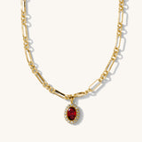 Gold necklace with a red gemstone pendant on a white background