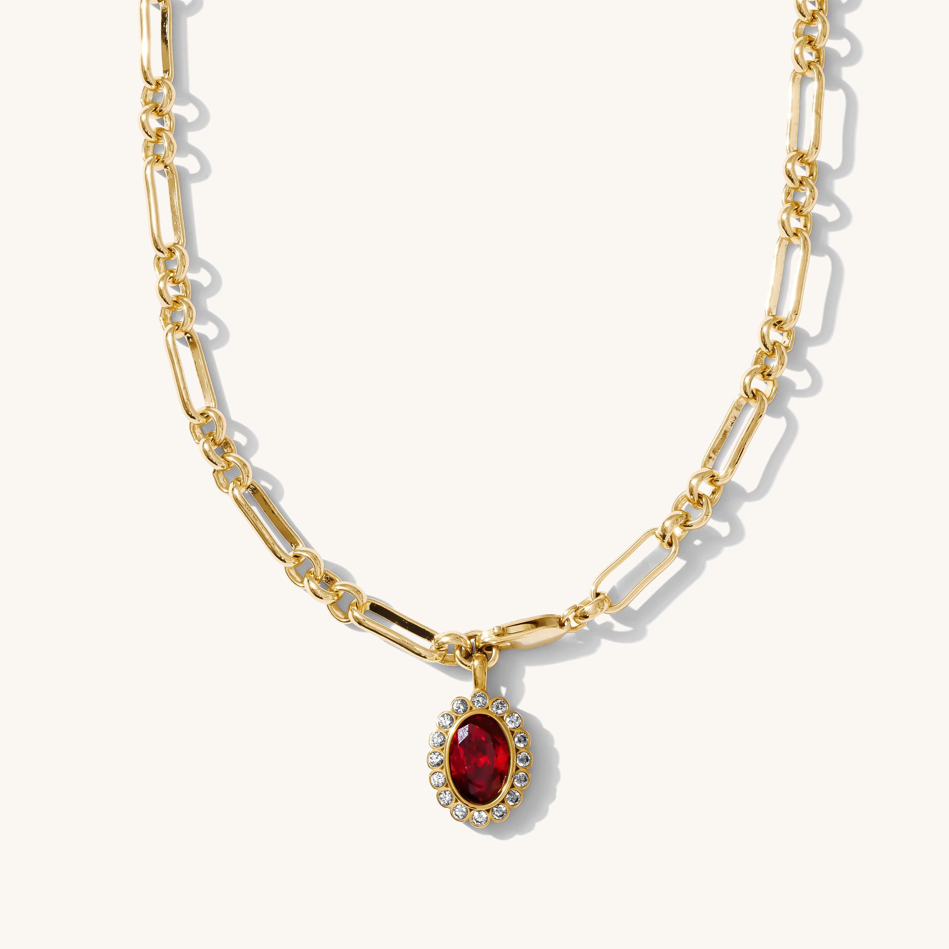 Gold necklace with a red gemstone pendant on a white background