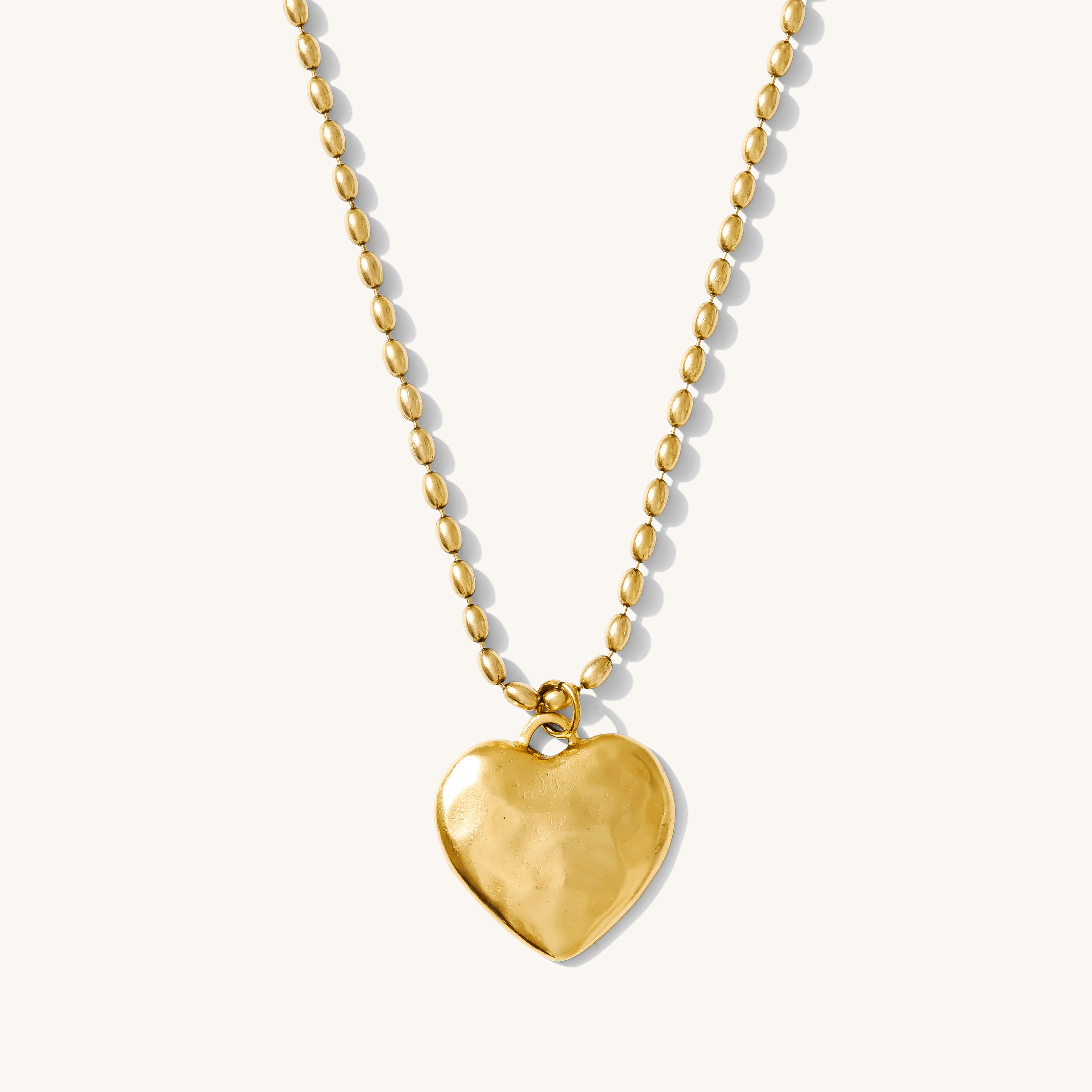 Gold heart-shaped pendant necklace on a white background