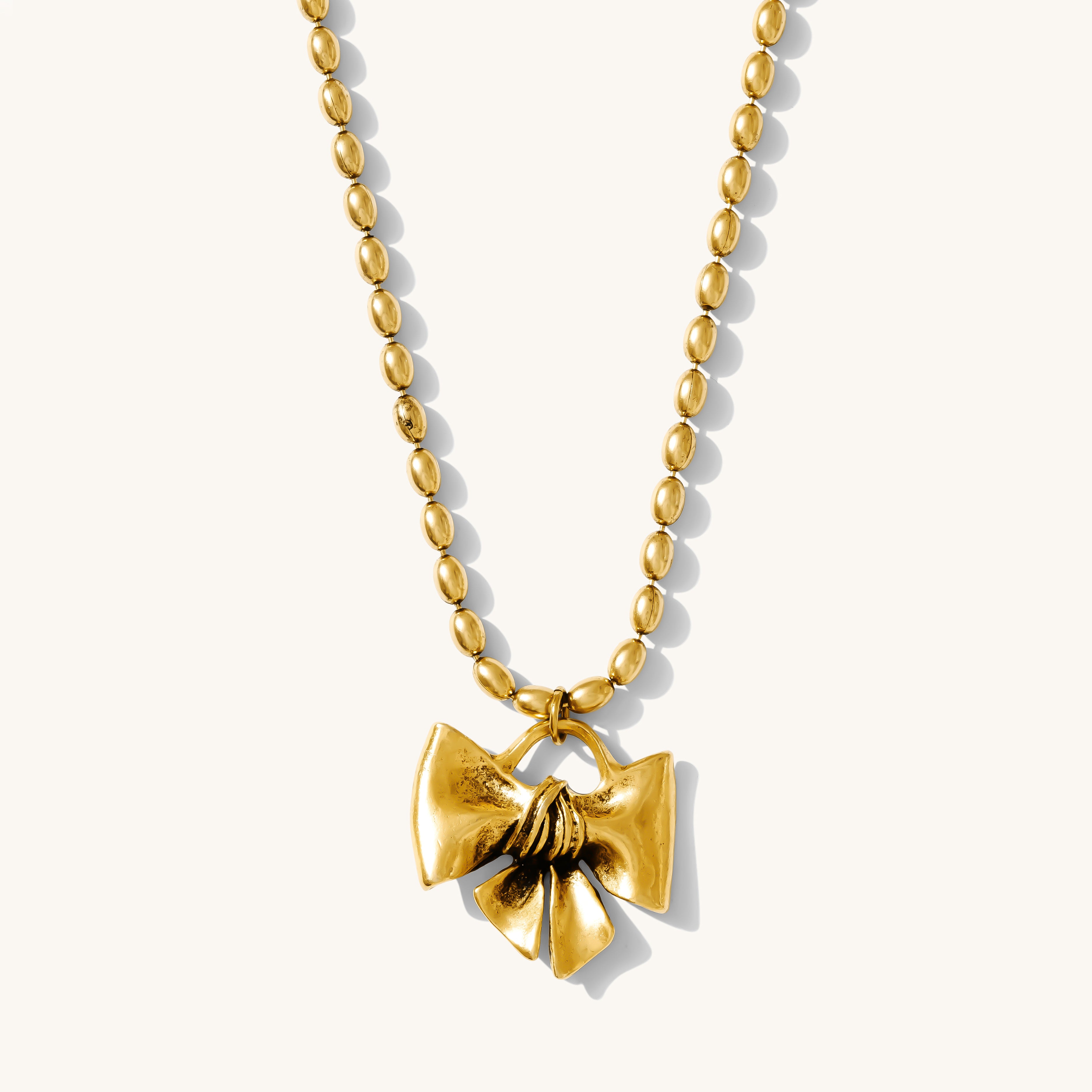 Gold necklace with a bow pendant on a white background