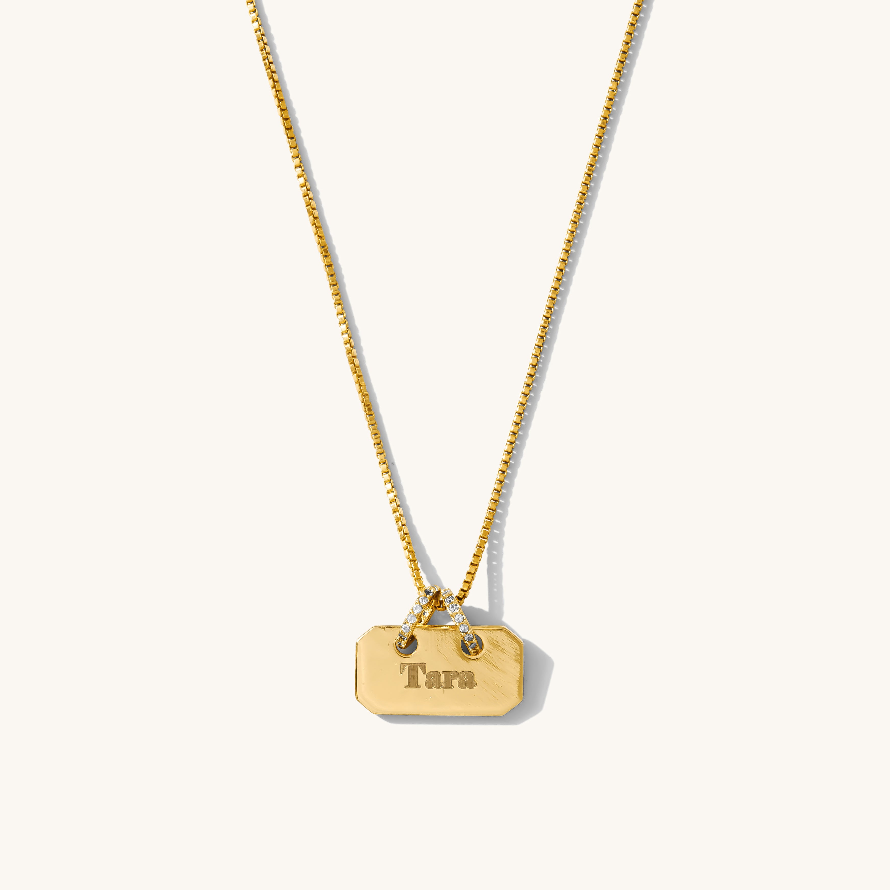 Gold necklace with a tag pendant on a white background