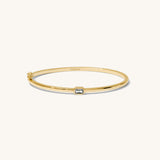 Gold bracelet with a small diamond on a white background