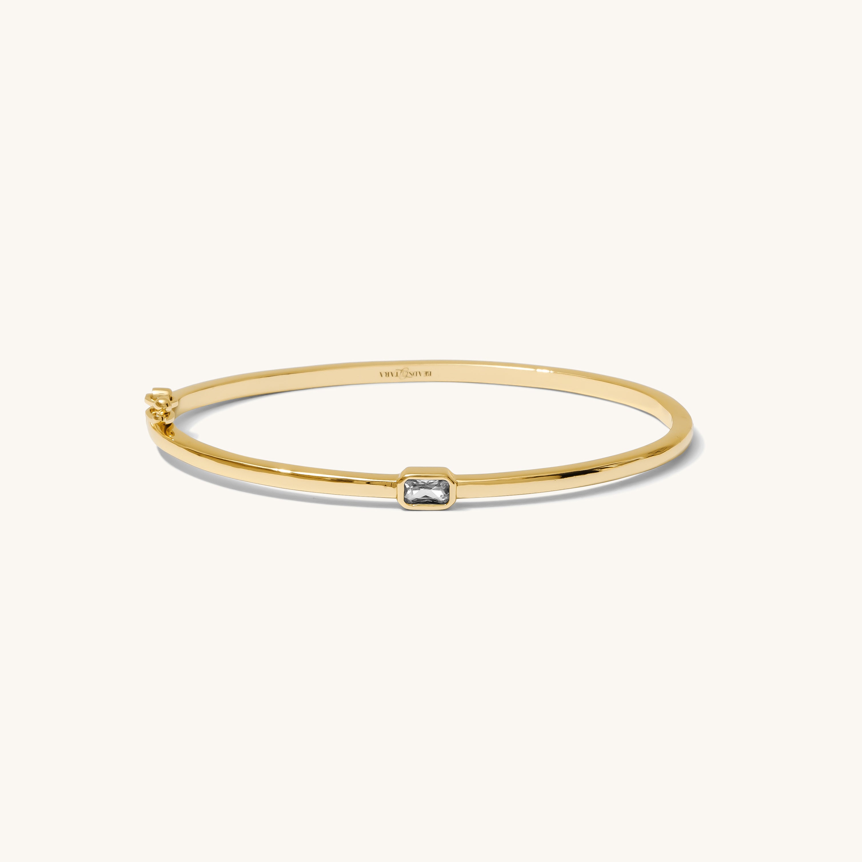 Gold bracelet with a small diamond on a white background
