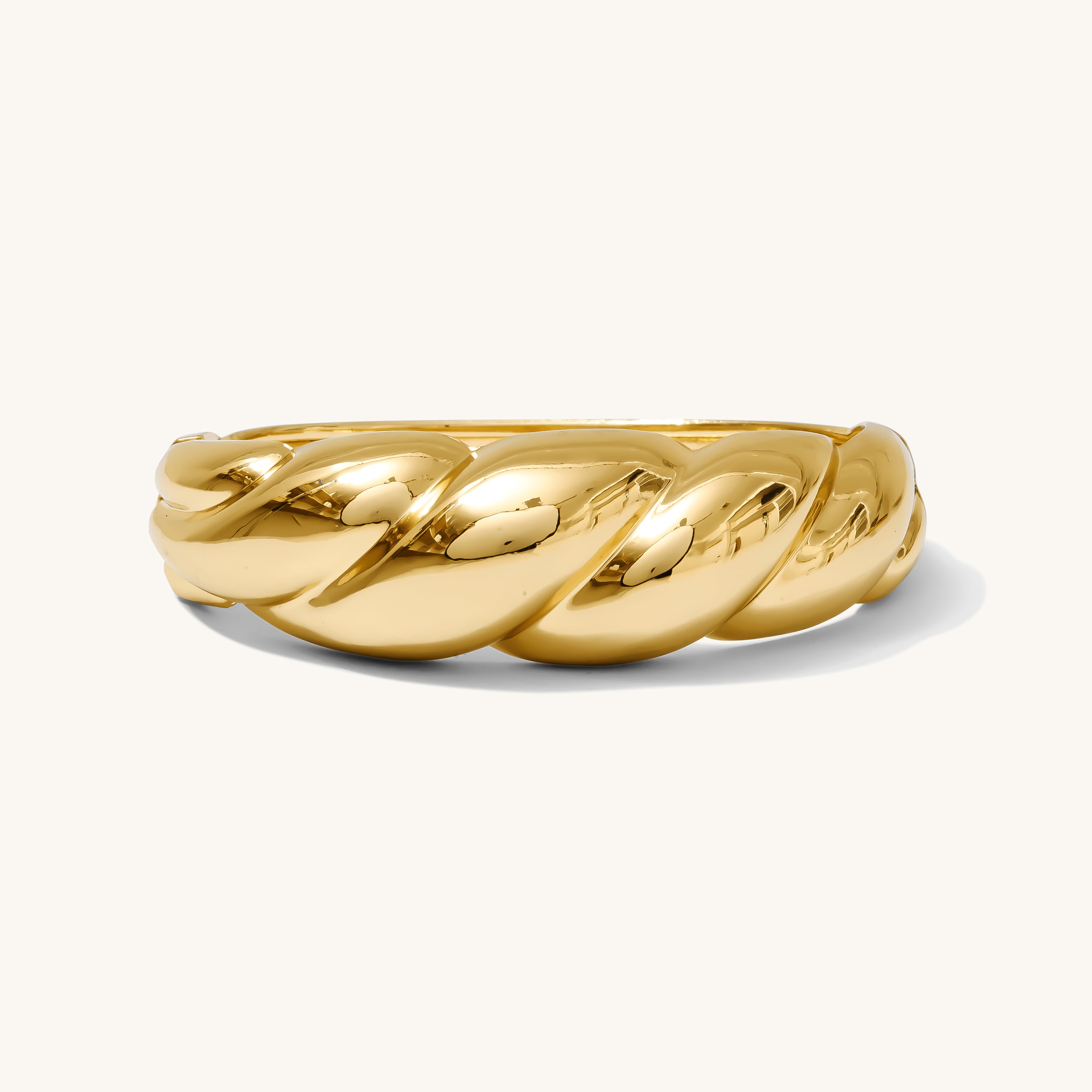 Gold ring with a twisted design on a white background