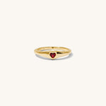 Gold ring with a red heart on a white background