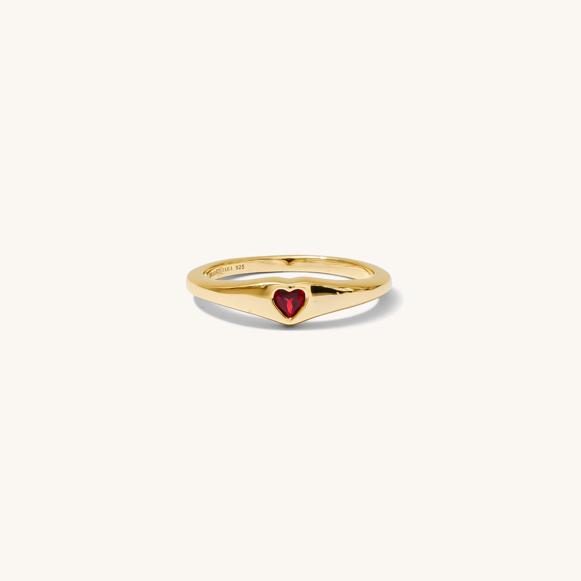 Gold ring with a red heart on a white background