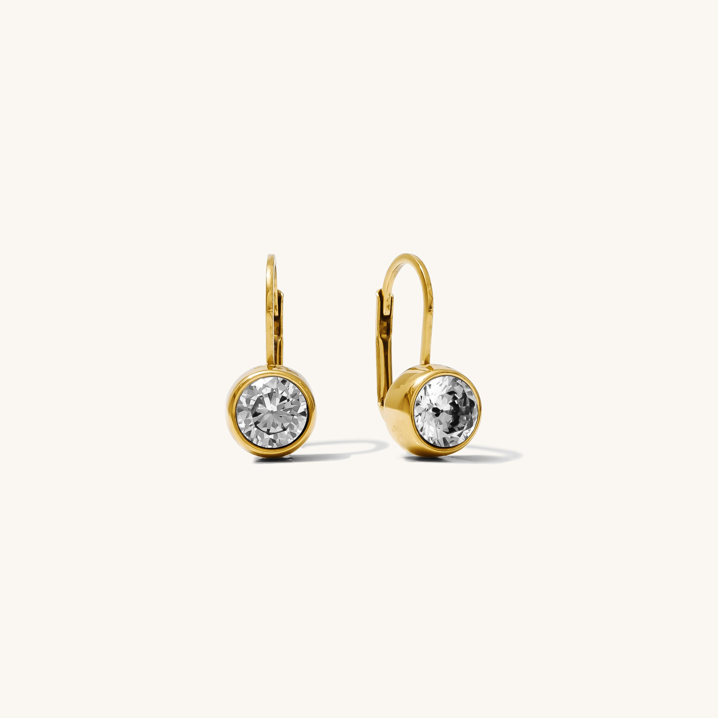Gold earrings with clear gemstones on a white background