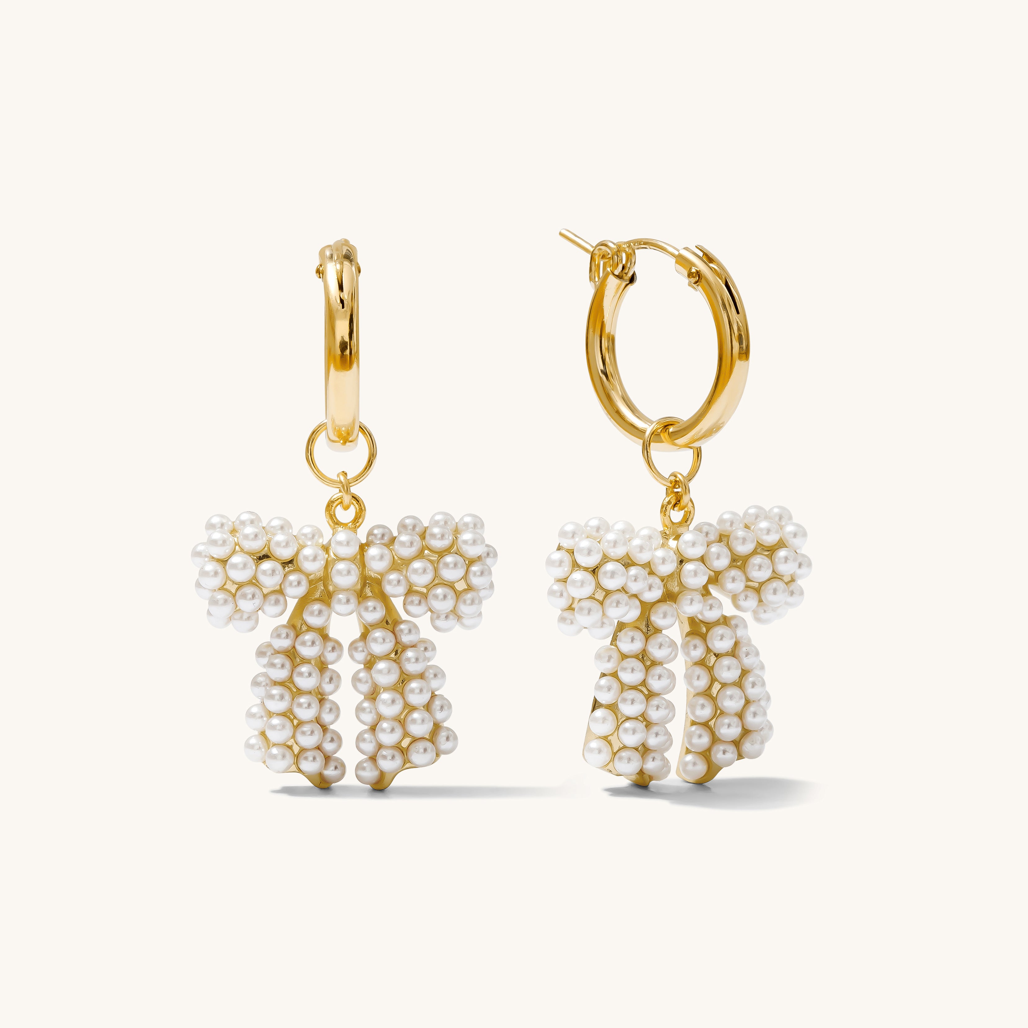 Close up of gold huggie earrings with removable charms on a white background