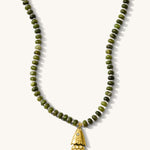 Close up of the olive Pez necklace with its articulated fish charm on a white background