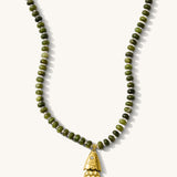 Close up of the olive Pez necklace with its articulated fish charm on a white background