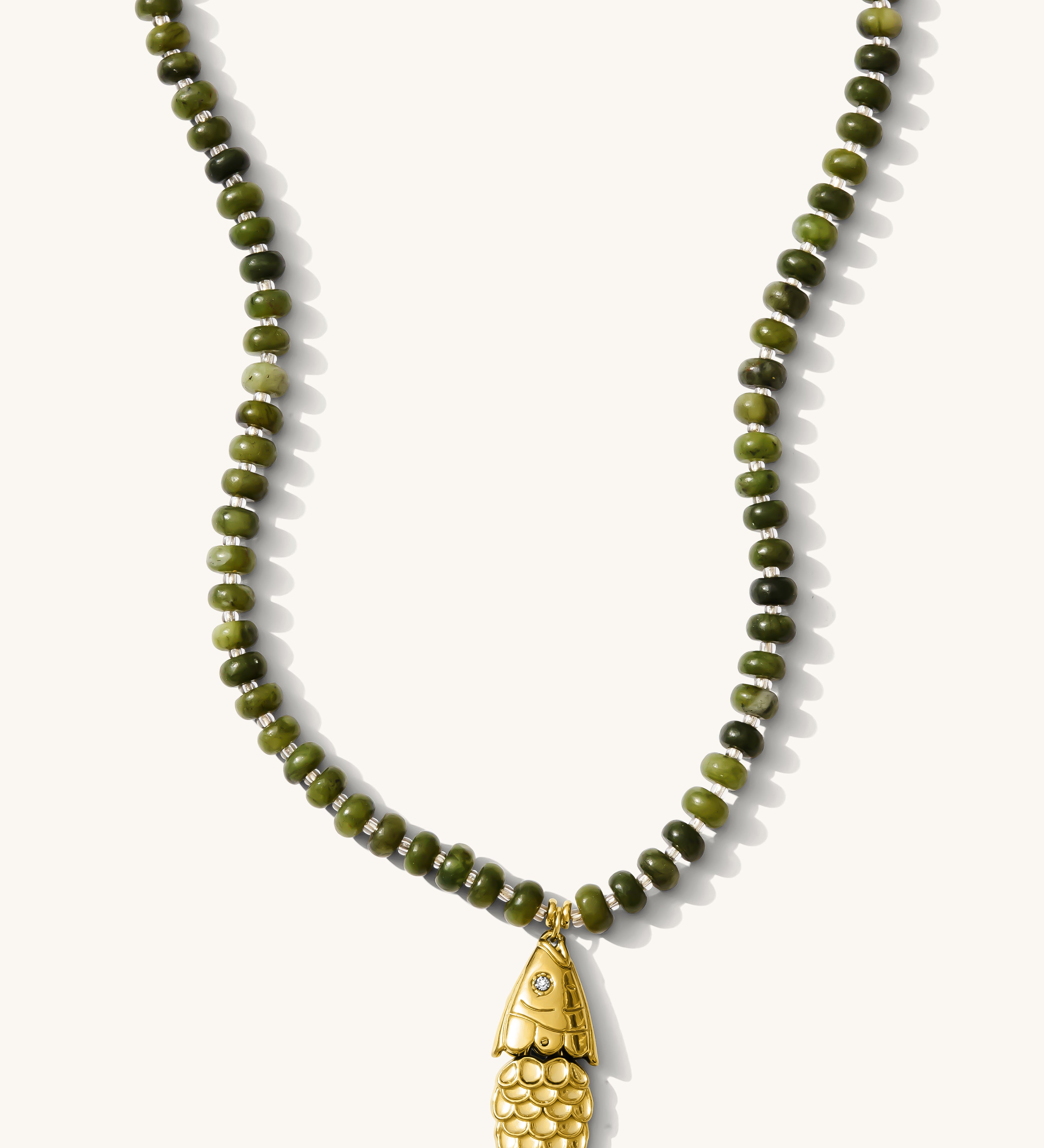Close up of the olive Pez necklace with its articulated fish charm on a white background