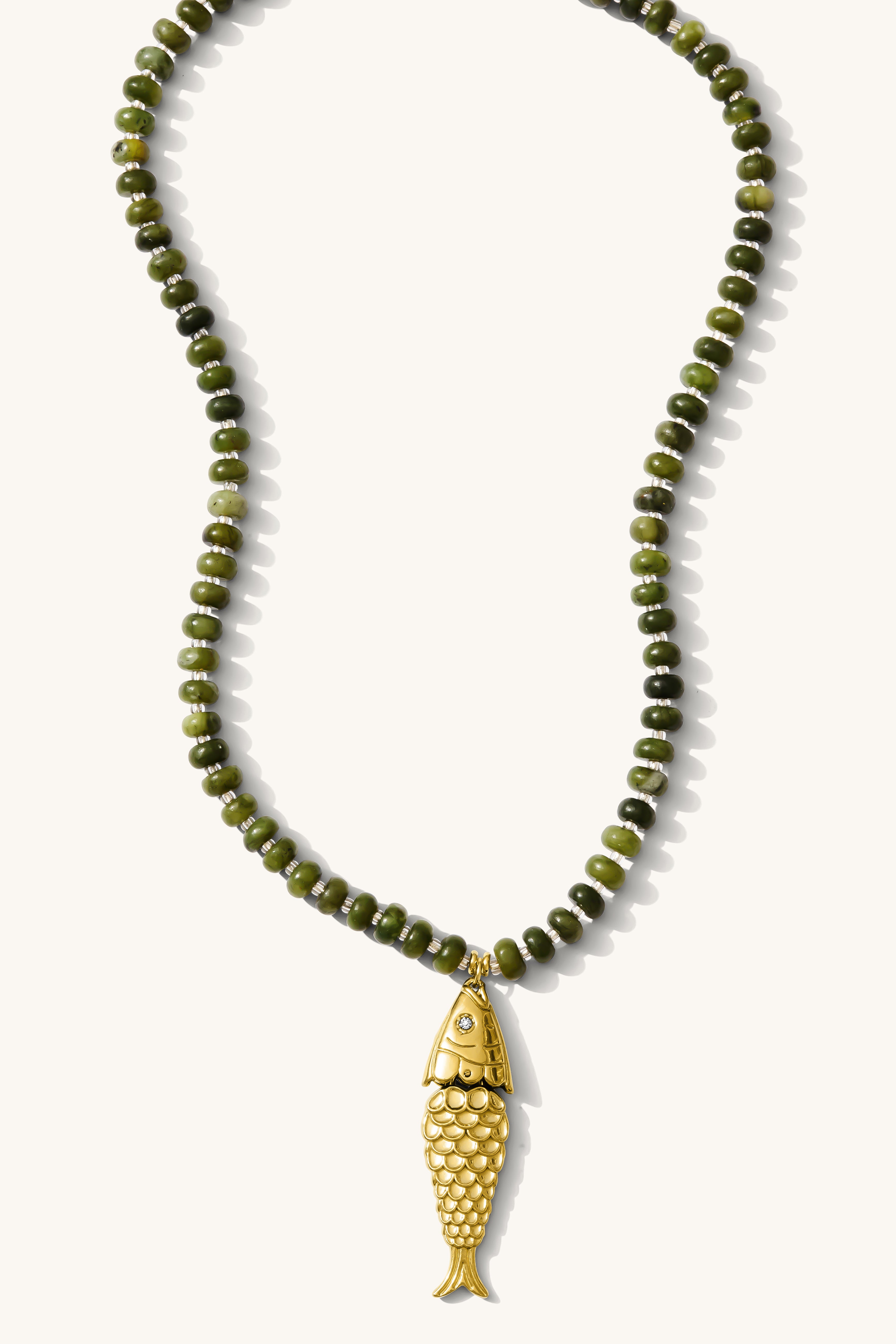 Close up of the olive Pez necklace with its articulated fish charm on a white background