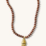 Close up of the Pez necklace in bronze gemstones with a fish charm on a white background