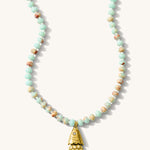 Close up of the turquoise Pez necklace with a vintage fish charm on a white background
