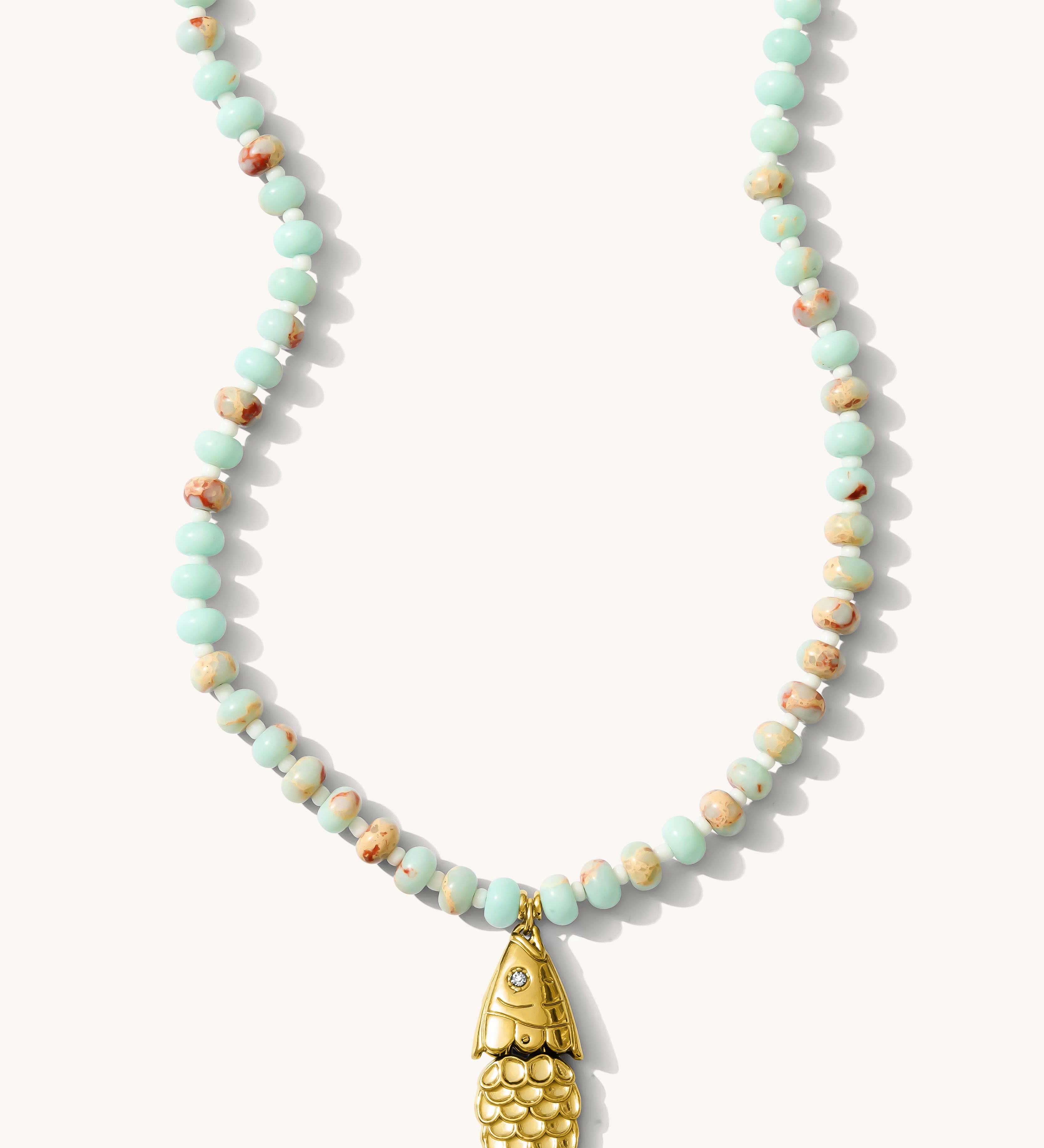 Close up of the turquoise Pez necklace with a vintage fish charm on a white background