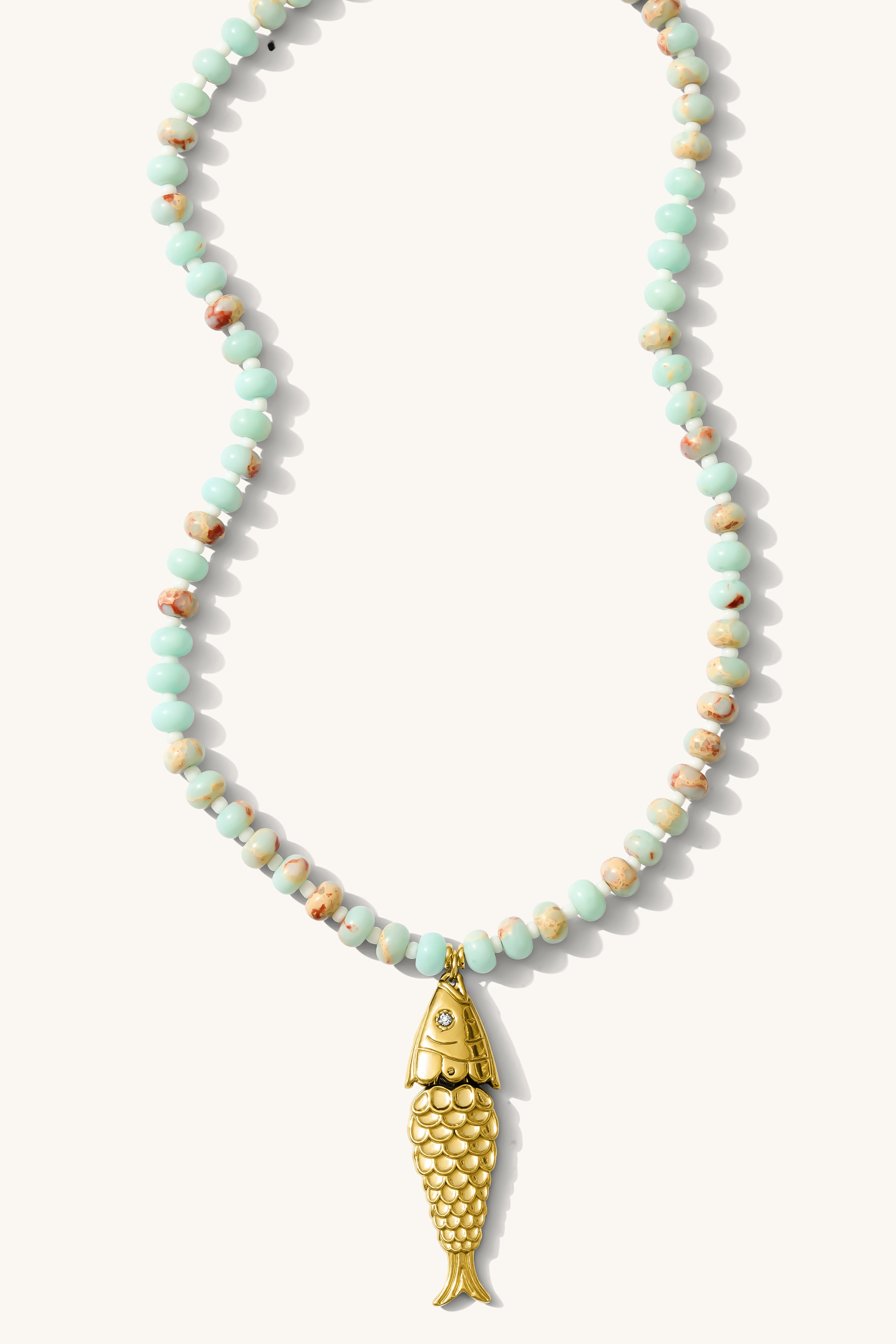 Close up of the turquoise Pez necklace with a vintage fish charm on a white background