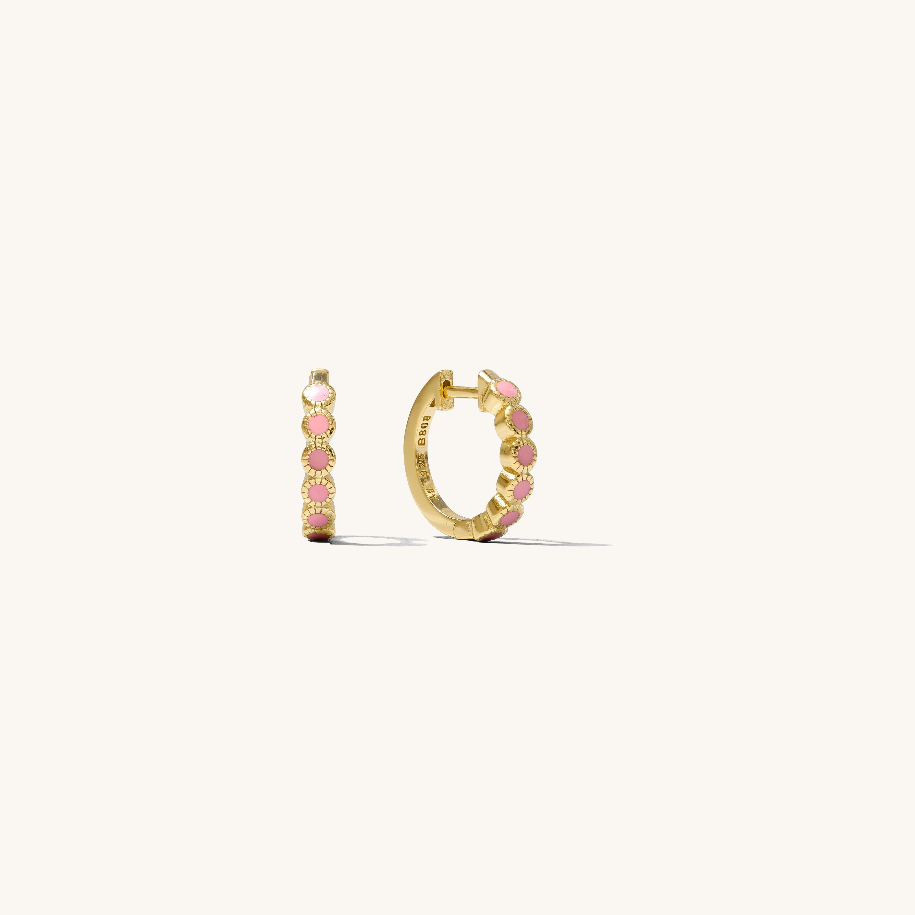 Close up of gold hoops with pink accents on a white background 