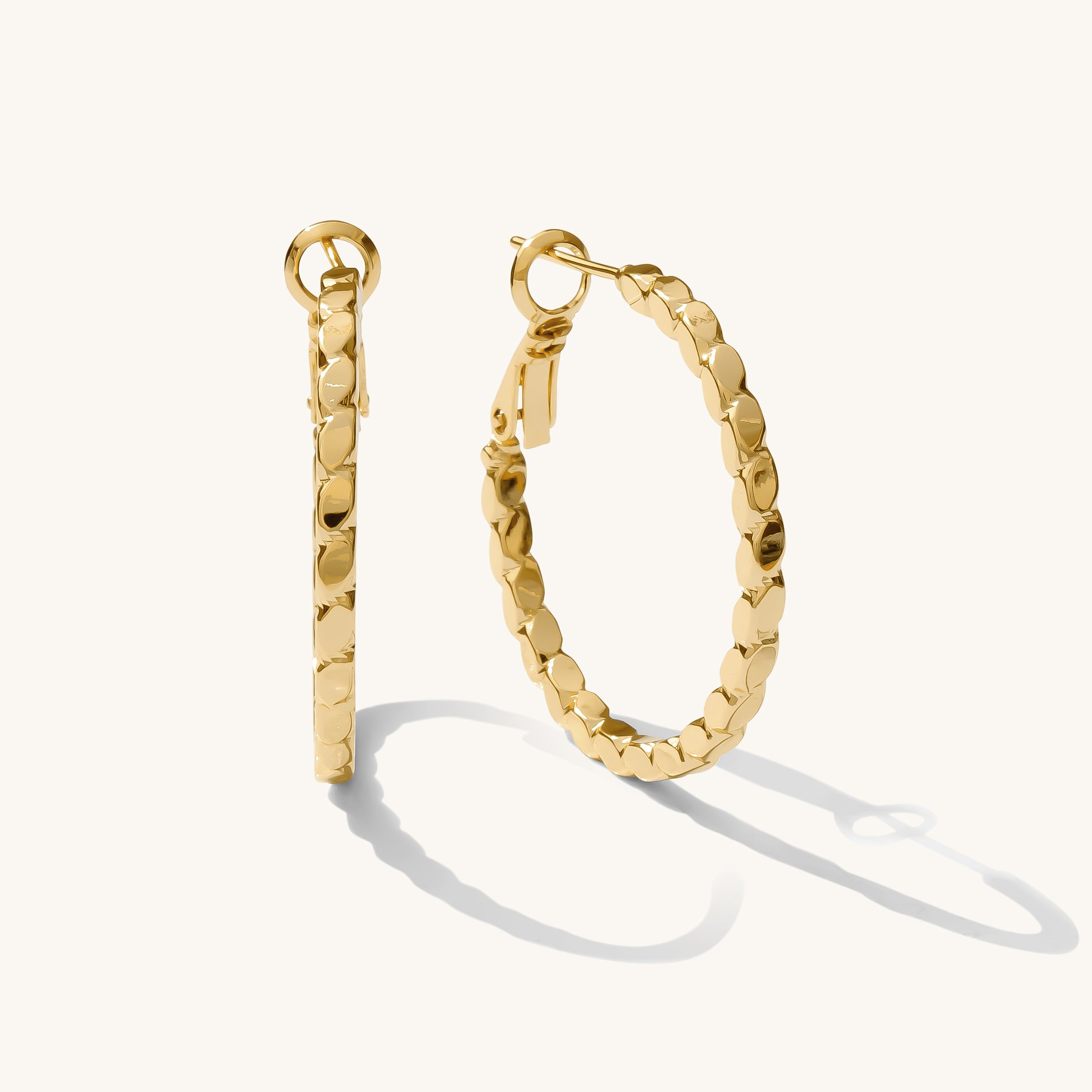 Close up of textured gold earrings on a white background