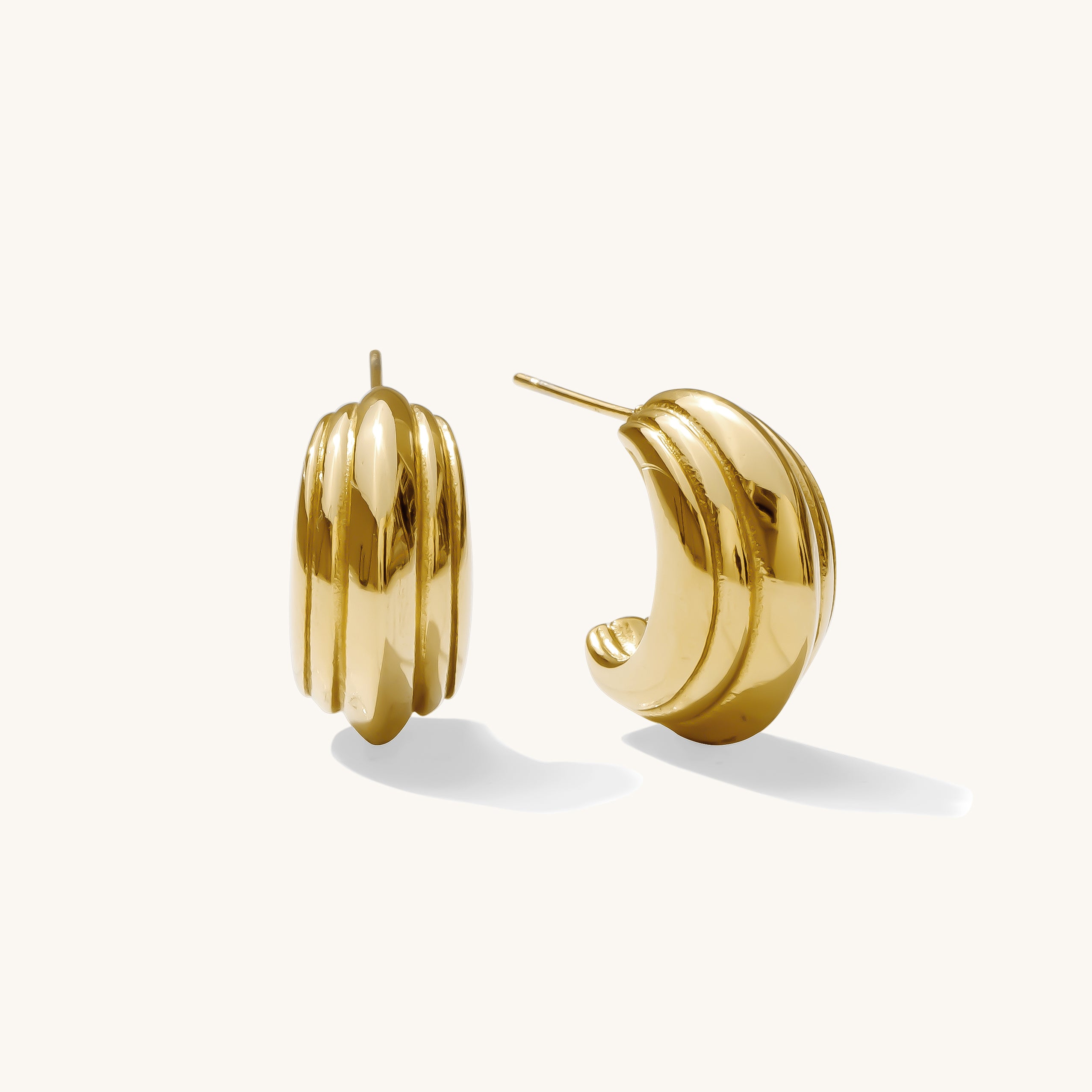 Close up of textured gold earrings on a white background