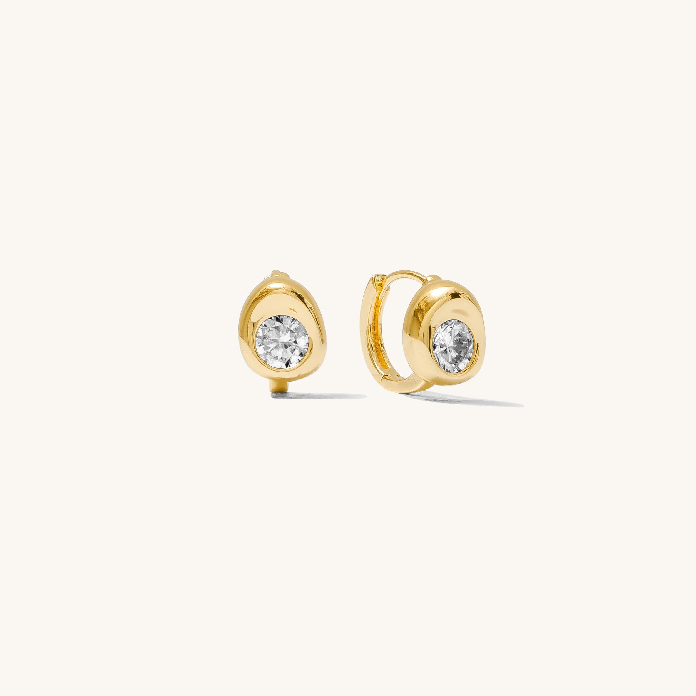 Close up of stone accented gold earrings on a white background