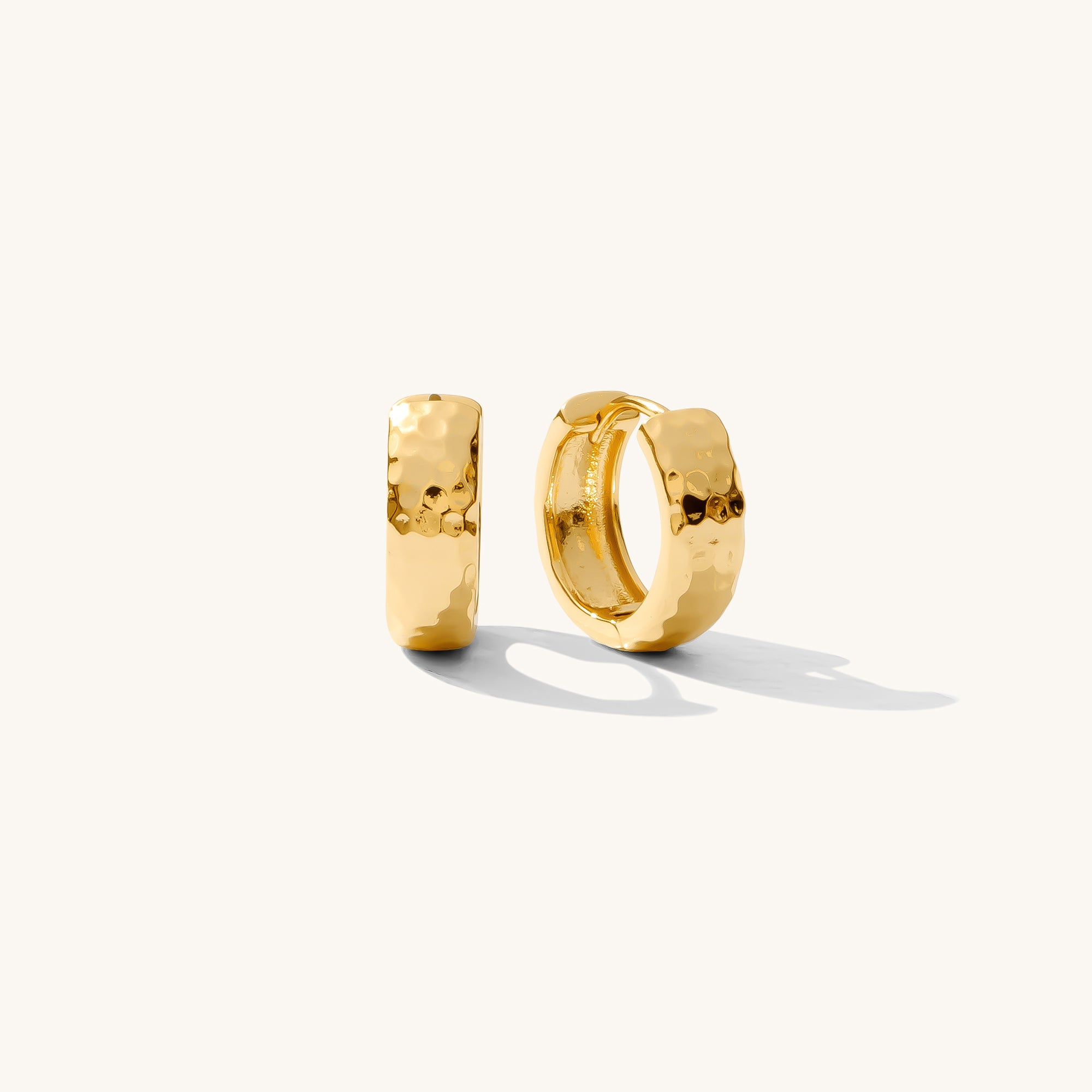 Close up of textured gold earrings on a white background