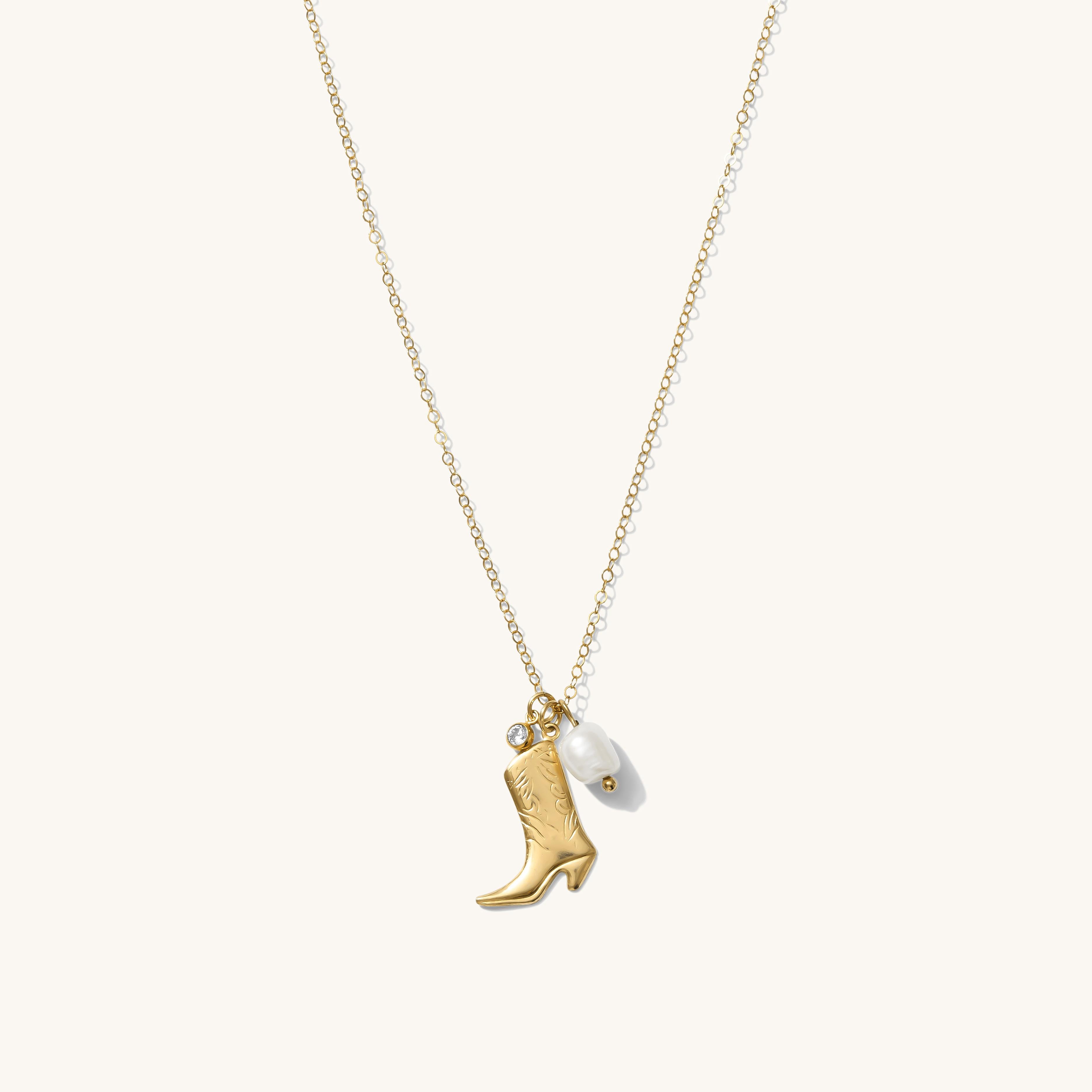 Gold necklace with a cowboy boot charm and pearl on a white background