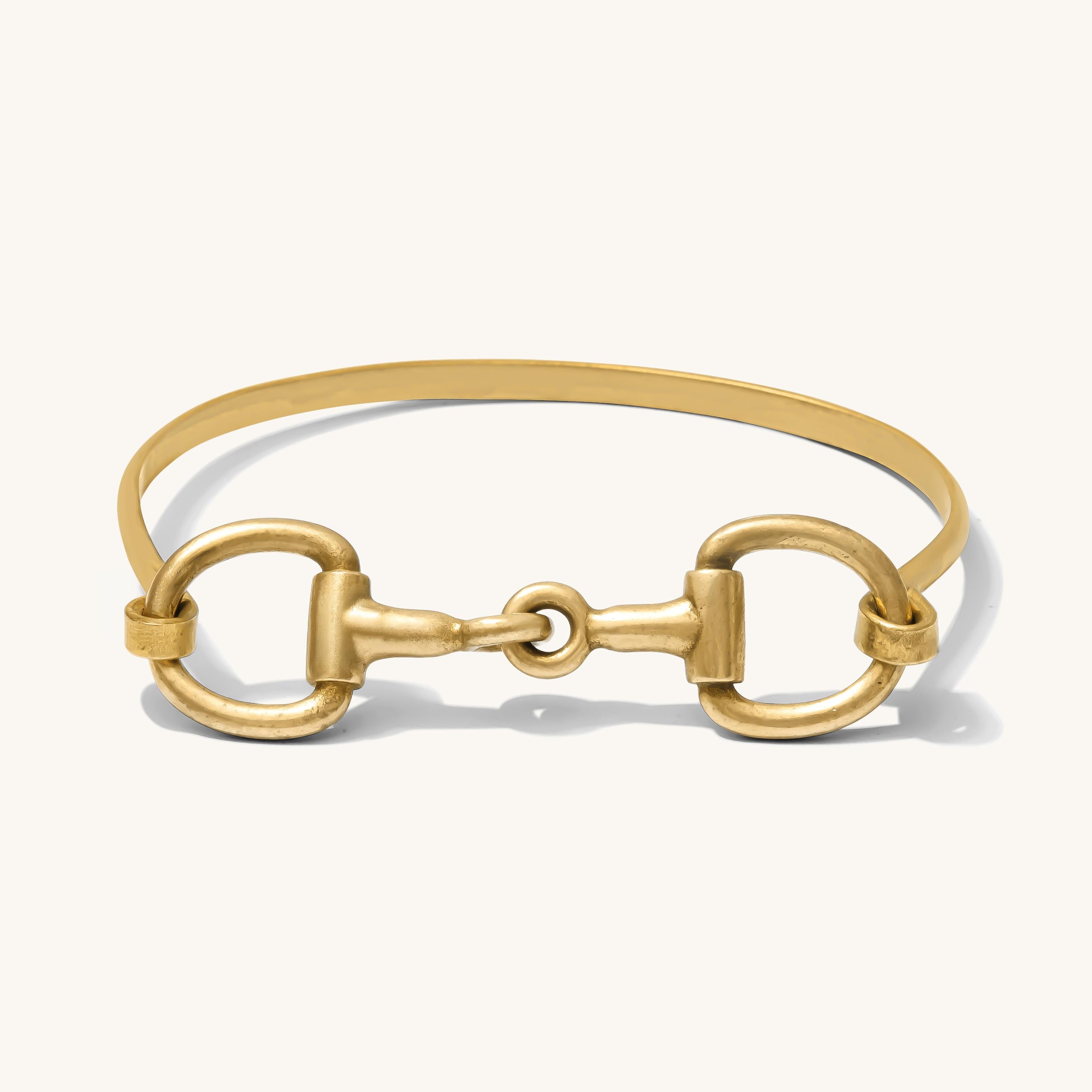 Gold bracelet with horsebit design on a white background
