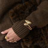 Close-up of a person wearing a brown coat with fur trim and gold bracelet.