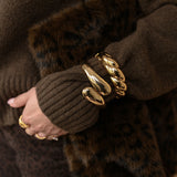 Close-up of a person wearing brown gloves with fur cuffs and gold bracelets.