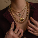 Close-up of a person wearing gold jewelry including necklaces, bracelets, and rings.
