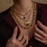 Close-up of a person wearing gold jewelry including necklaces, bracelets, and rings.