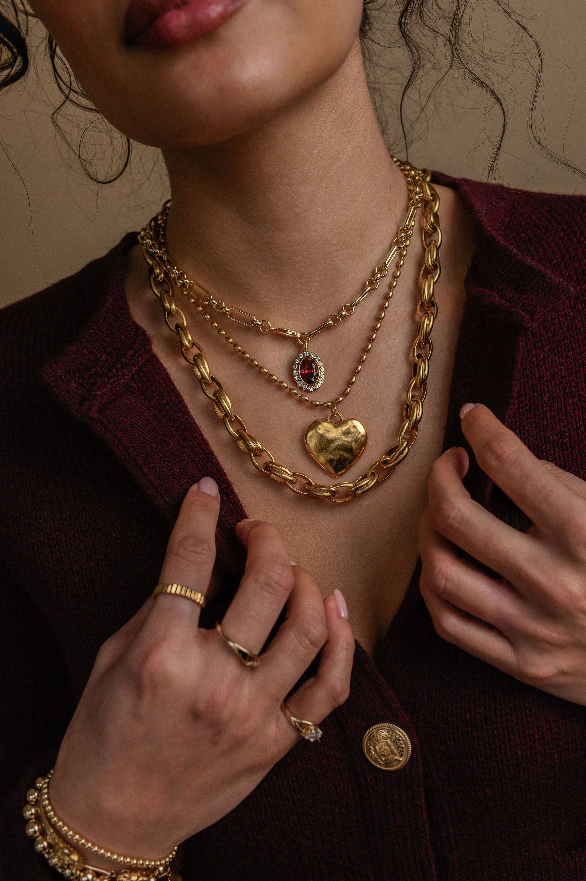 Close-up of a person wearing gold jewelry including necklaces, bracelets, and rings.