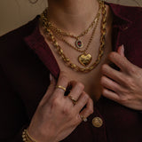 Close-up of a person wearing gold jewelry including necklaces, bracelets, and rings.