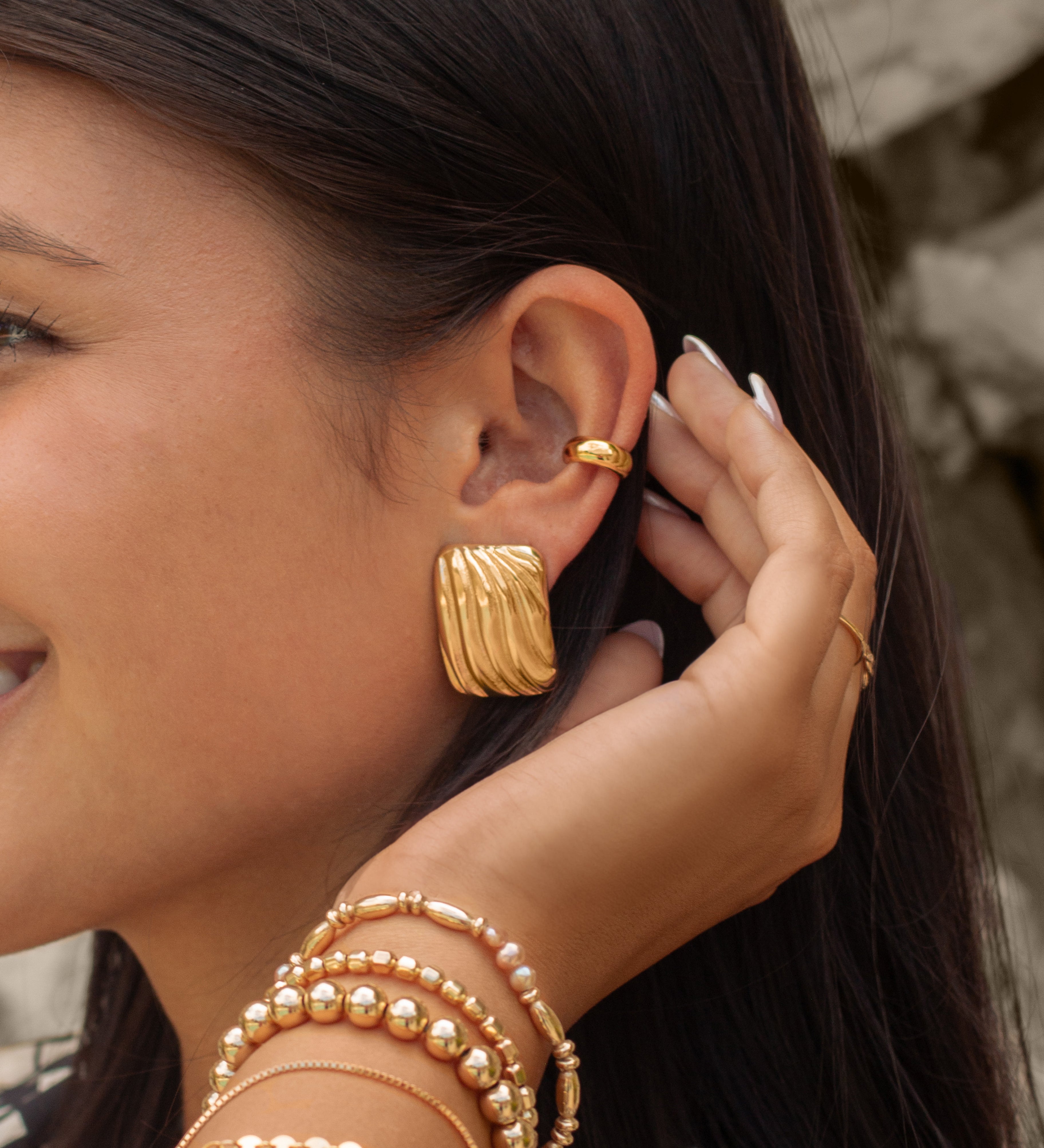 A woman wearing gold bracelets and earrings
