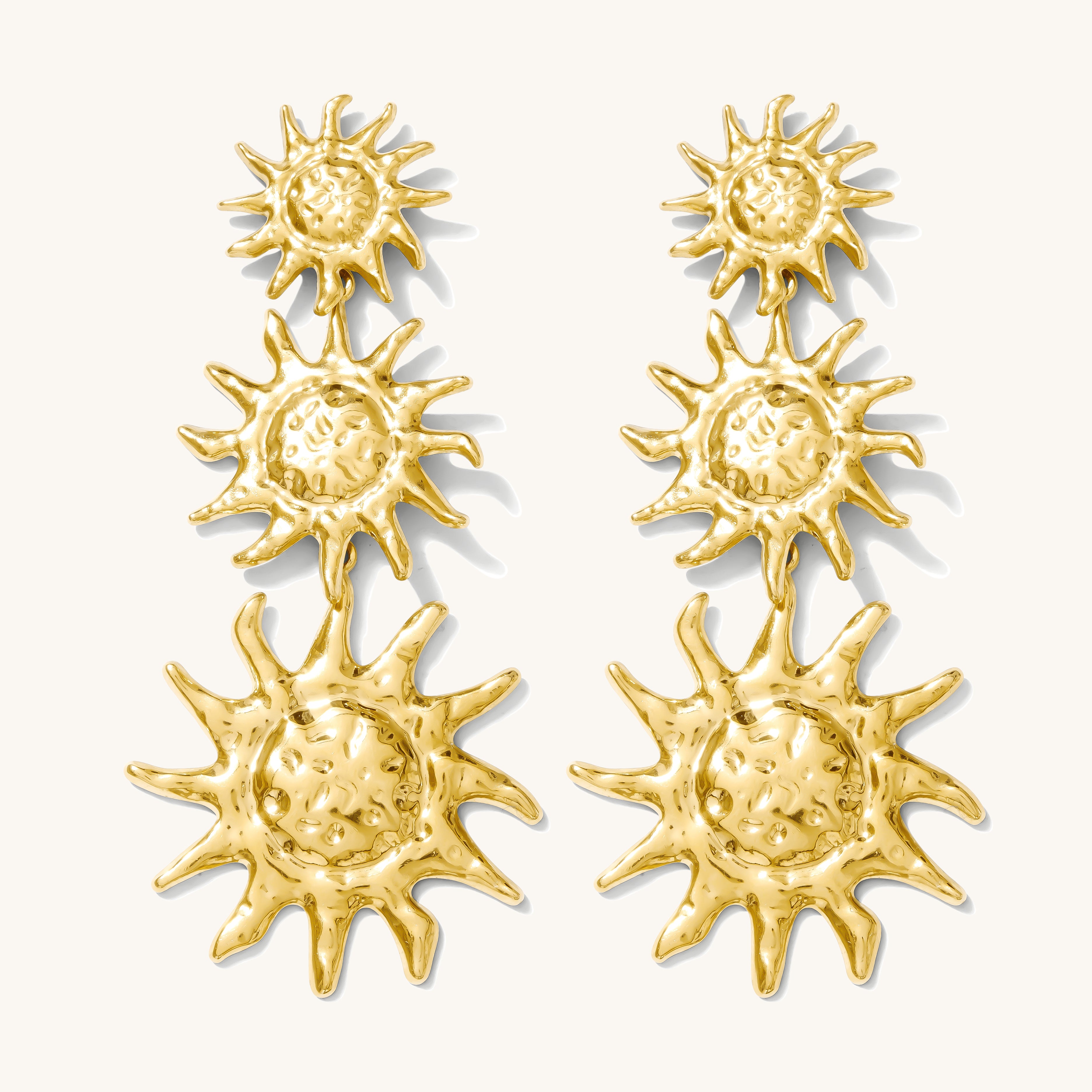 Close up of gold statement earrings on a white background