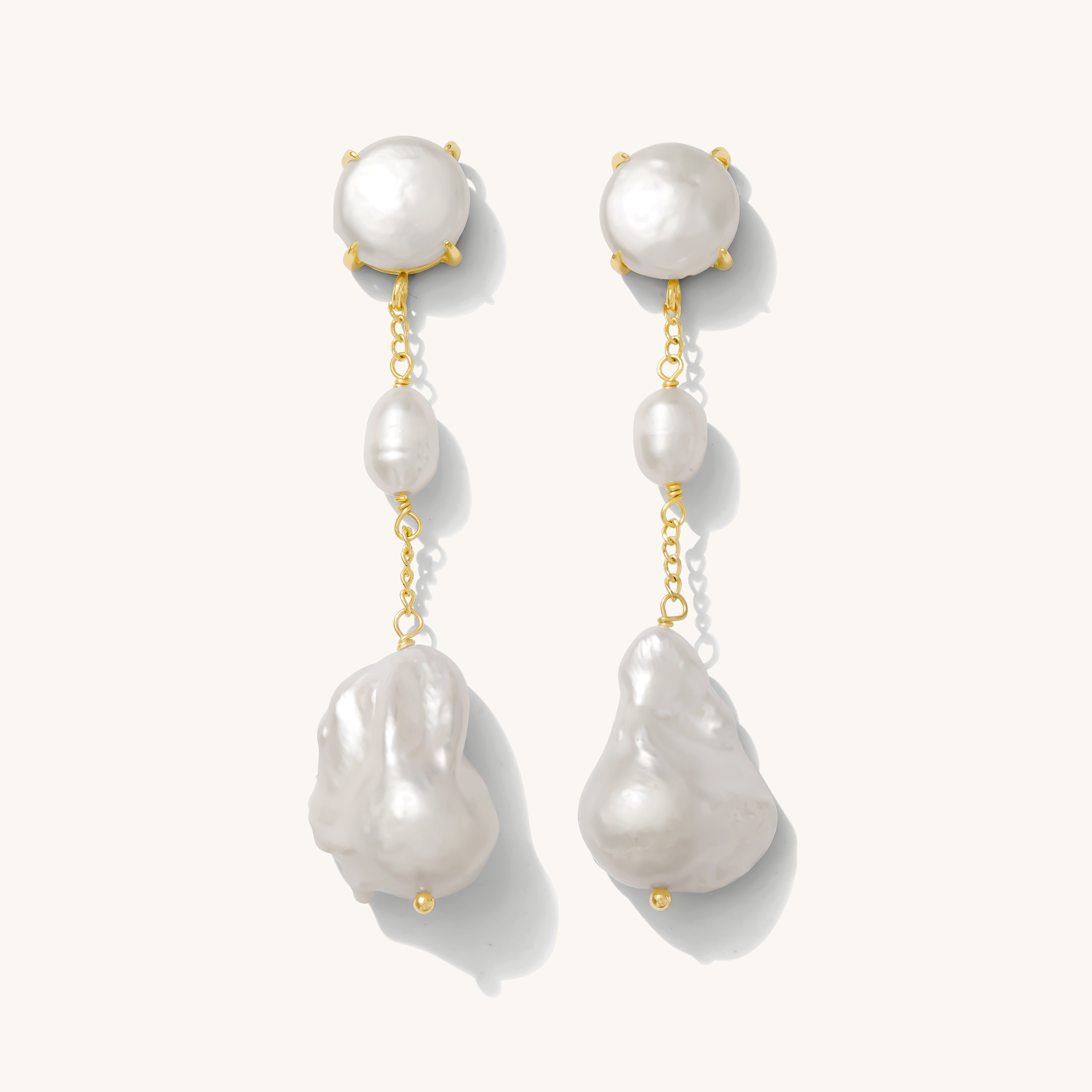 Close up of pearl dangle earrings on a white background
