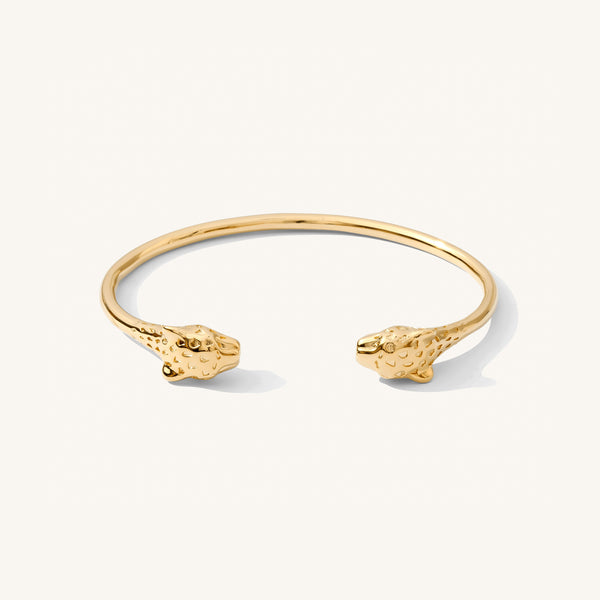 Close up of a gold cuff bracelet on a white background  