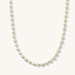 A white pearl necklace with gold accents, presented against a plain background.