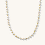 A white pearl necklace with gold accents, presented against a plain background.