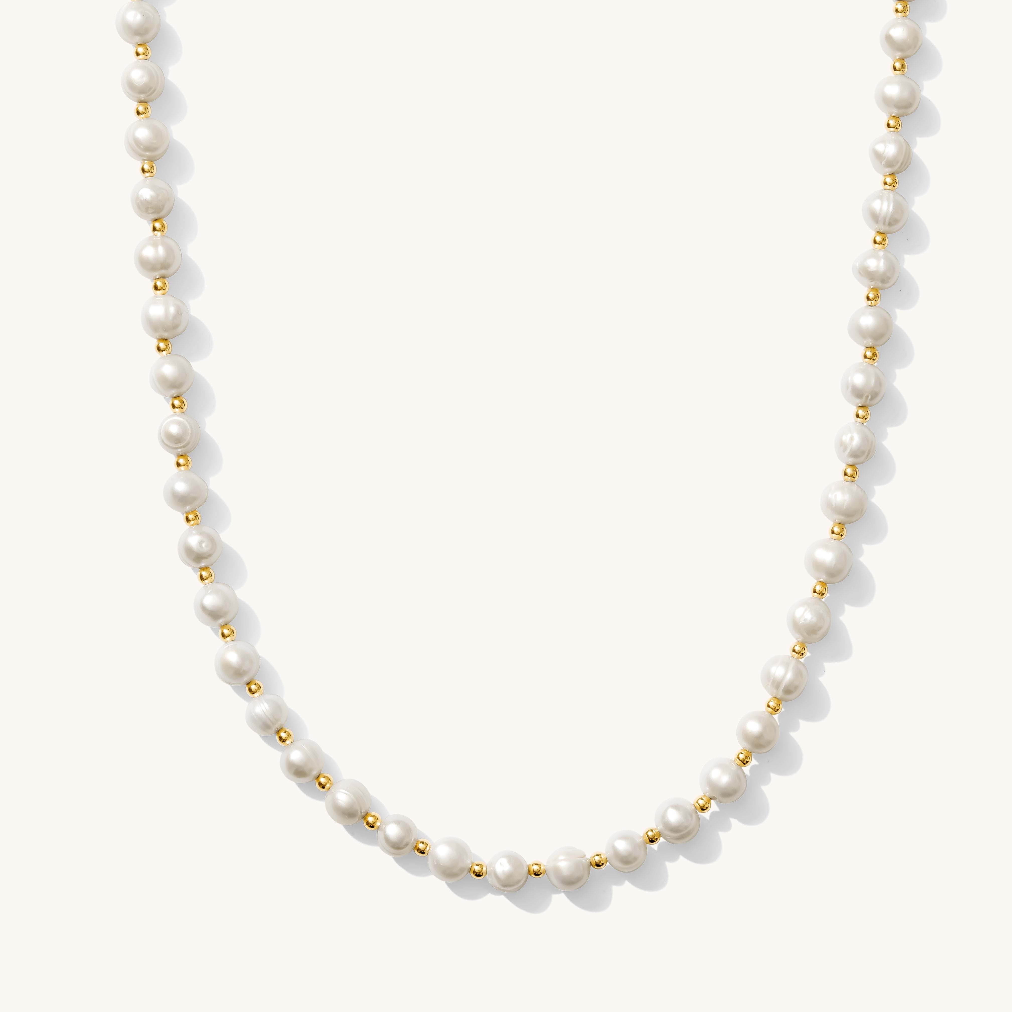 A white pearl necklace with gold accents, presented against a plain background.