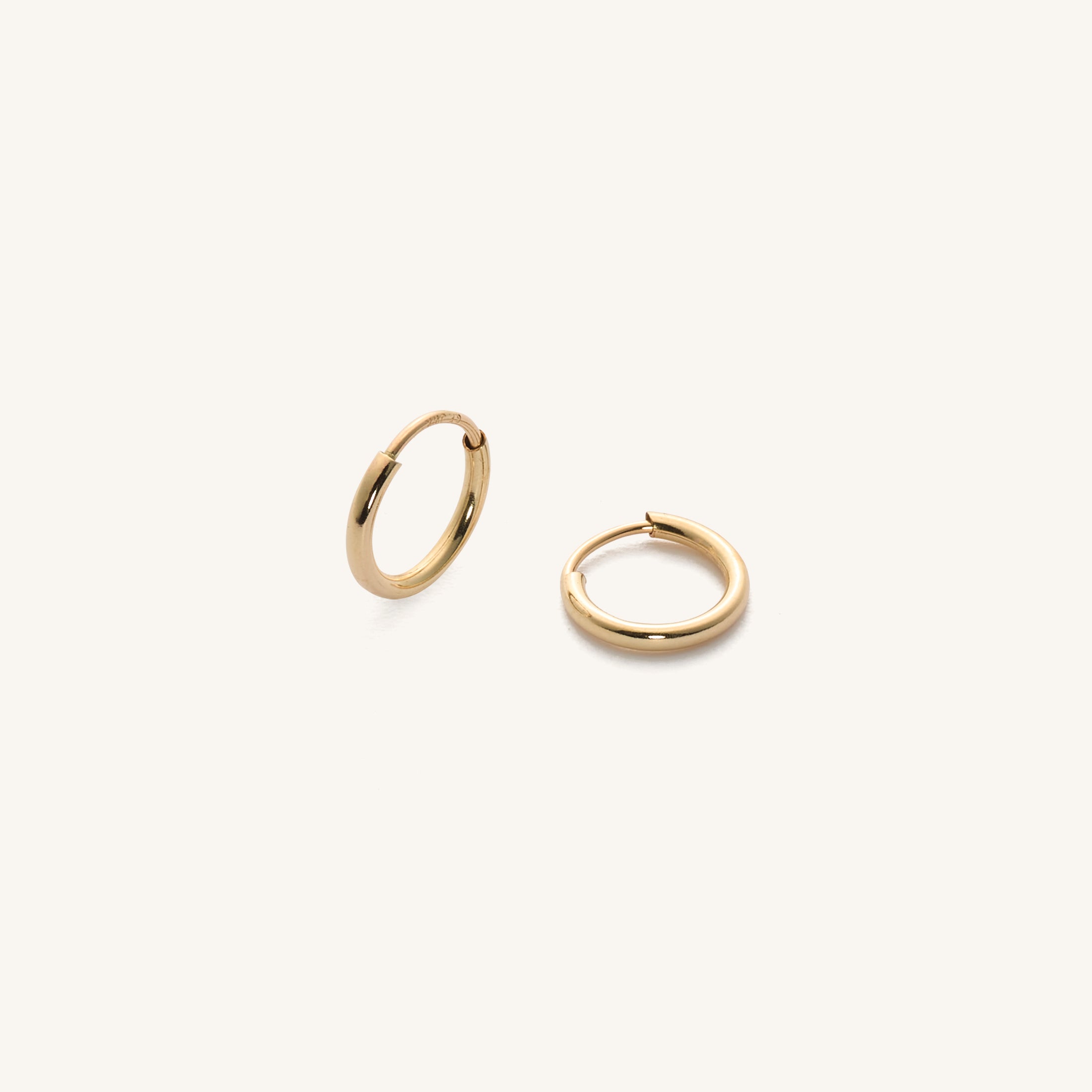 Close up of gold huggie earrings on a white background 