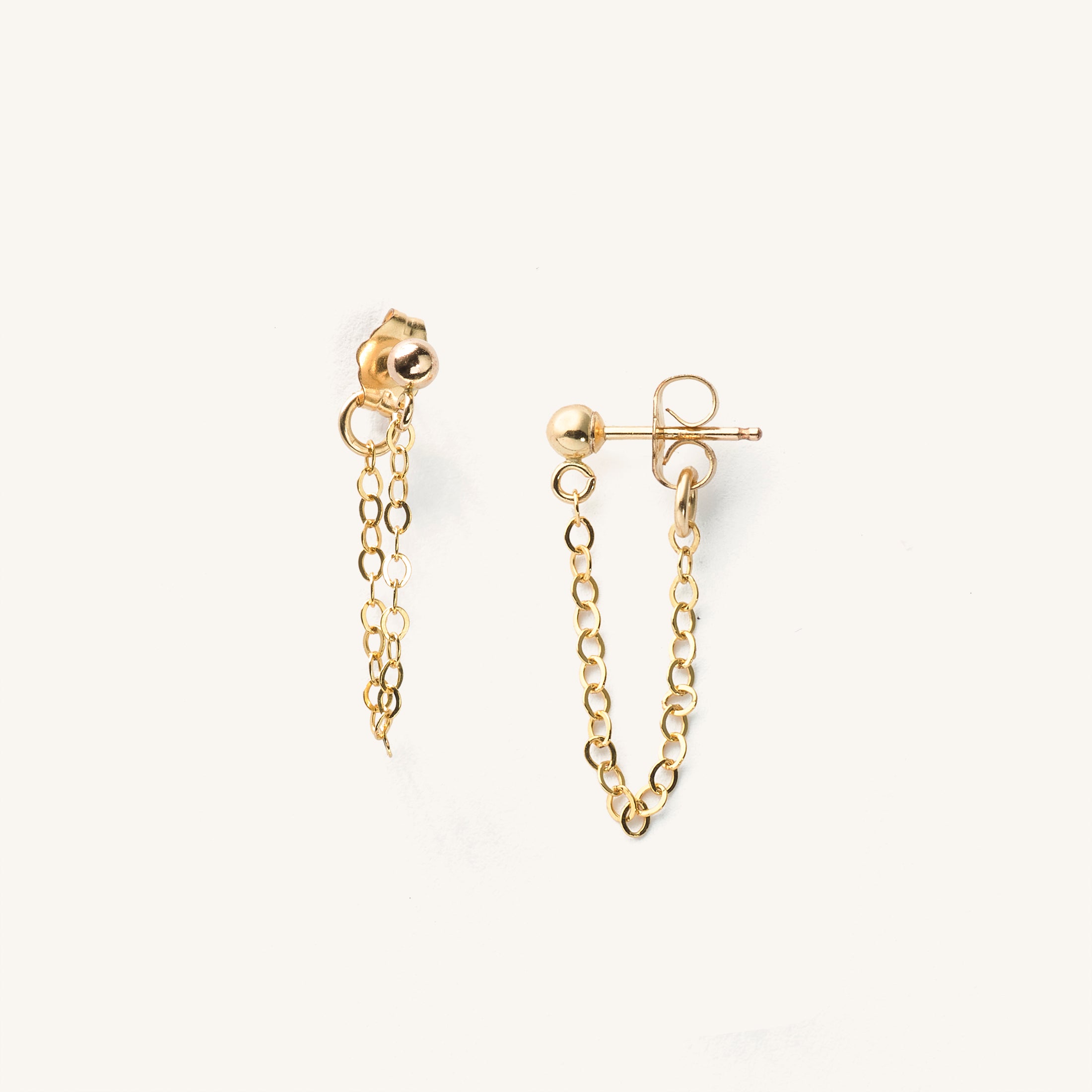 Close up of gold ball stud earrings with chain attachment 