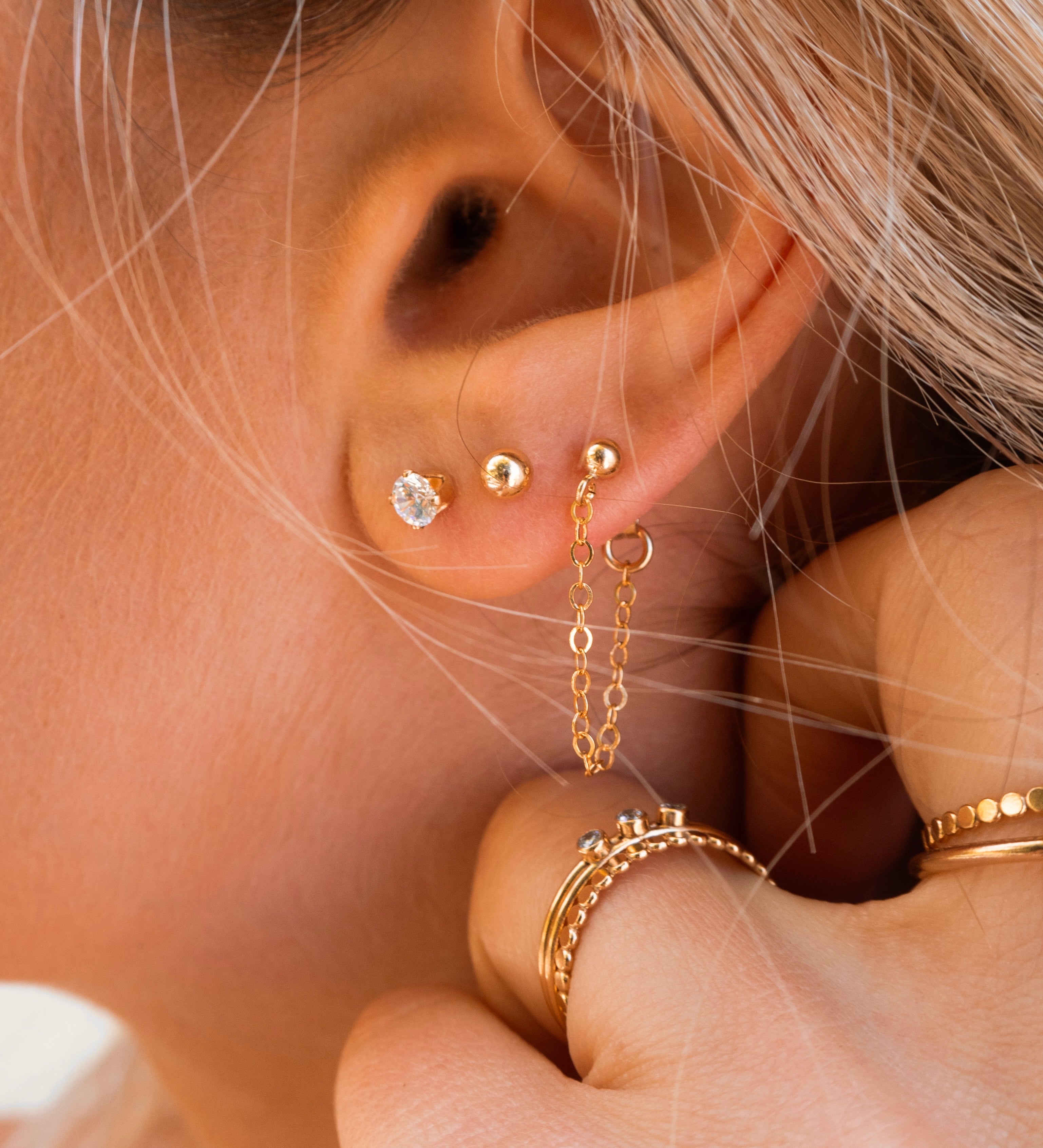 Close-up of an ear with multiple gold stud earrings 